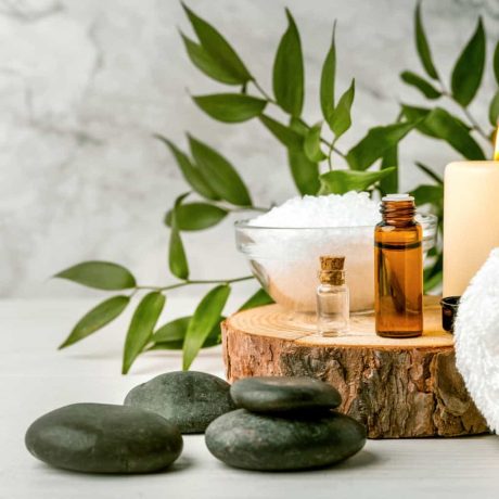 beauty treatment items for spa procedures on white wooden table. massage stones, essential oils and sea salt. copy space